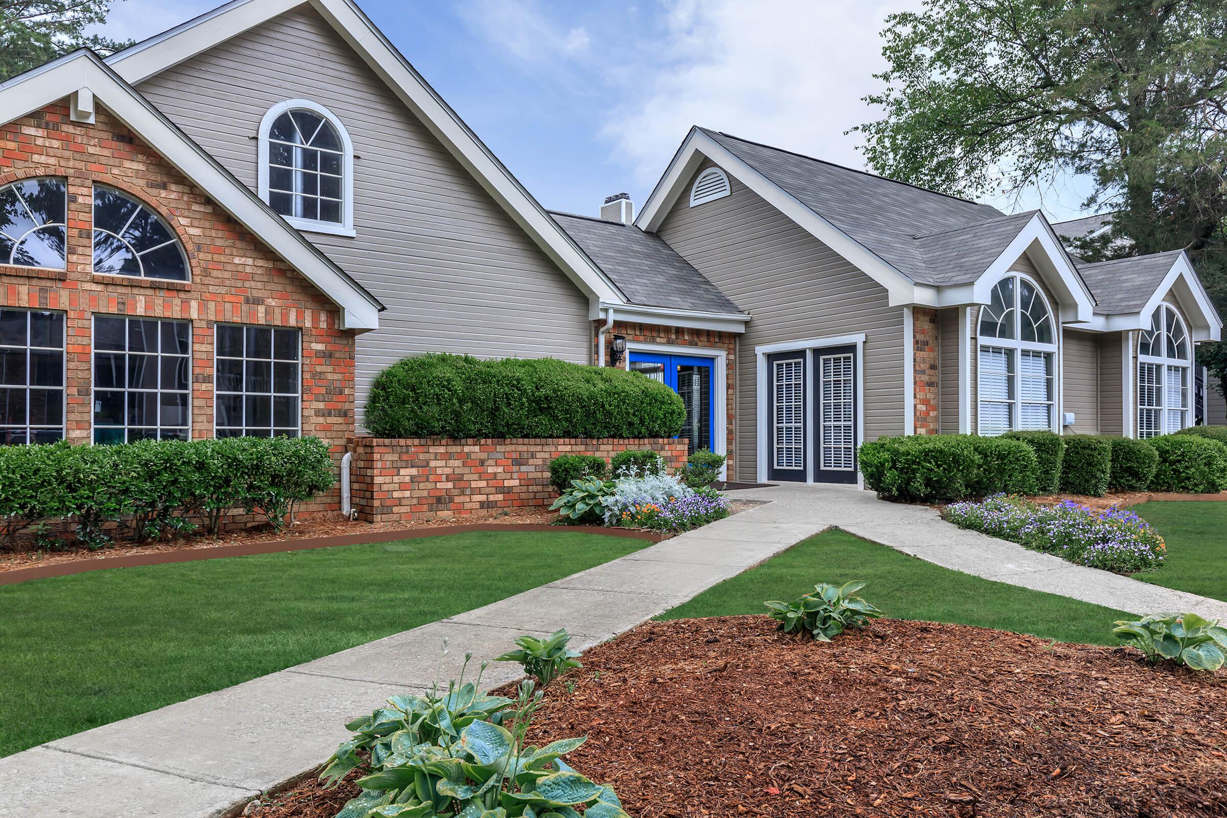 a house with a lawn in front of a brick building