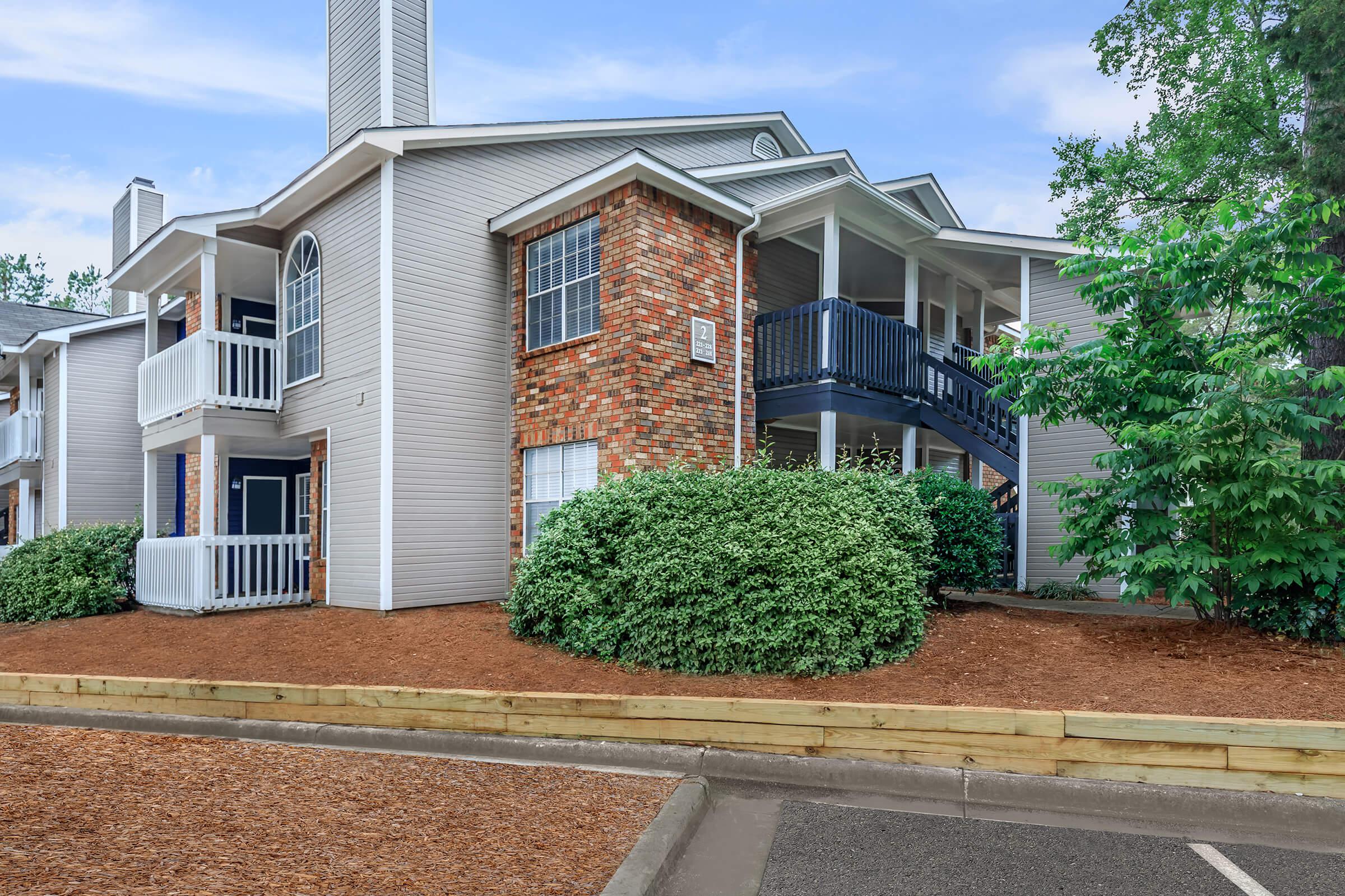 a house with trees in front of a brick building