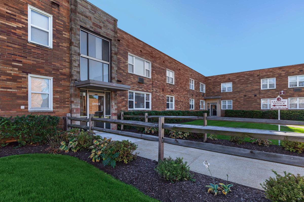 a large brick building with grass in front of a house