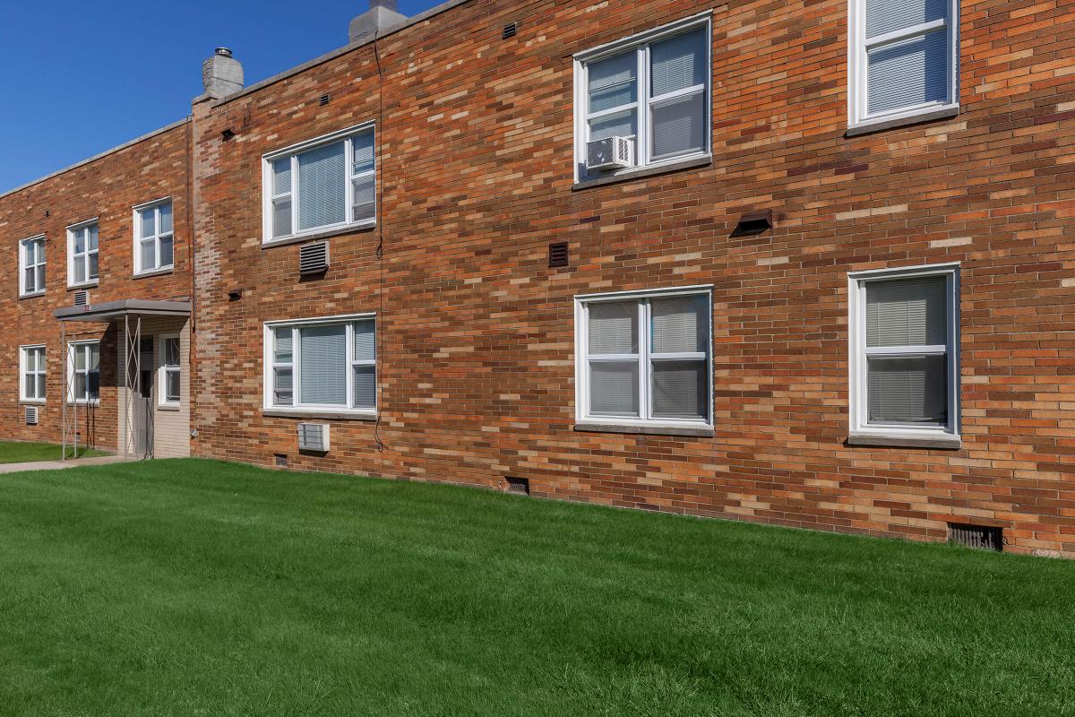 a large brick building with grass in front of a house