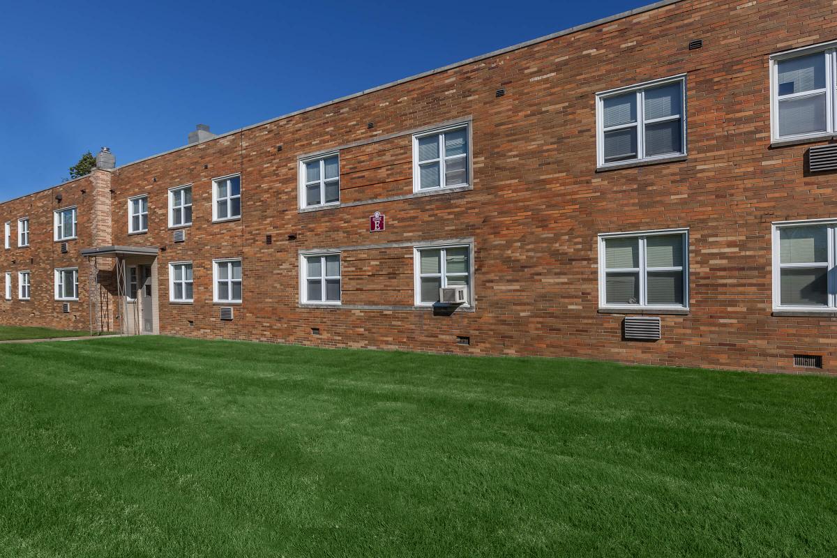 a large brick building with grass in front of a house