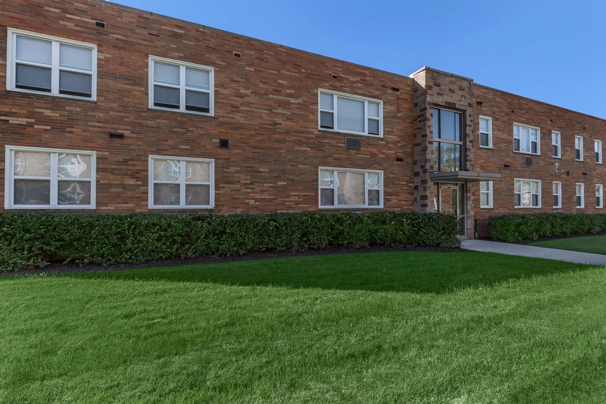 a large brick building with grass in front of a house