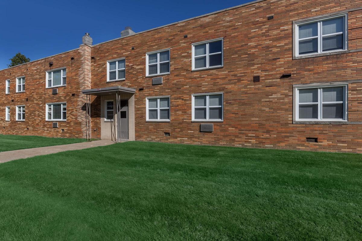 a large brick building with grass in front of a house