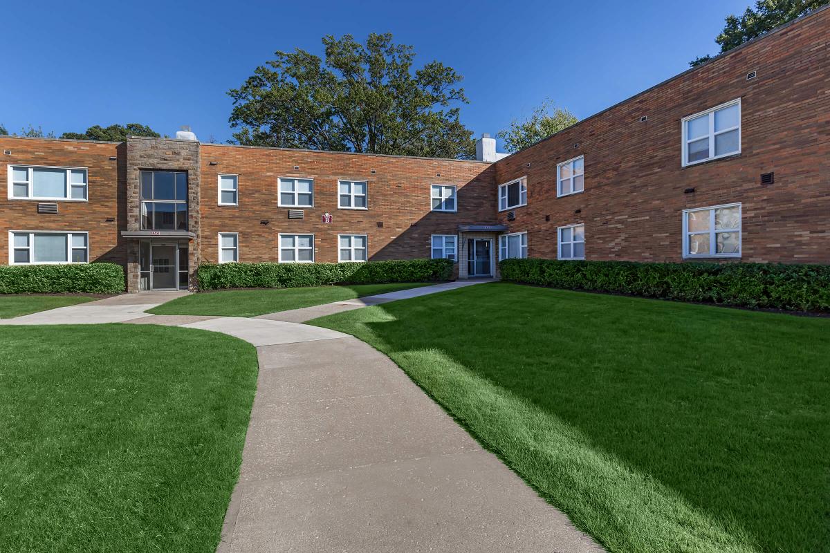 a large brick building with grass in front of a house