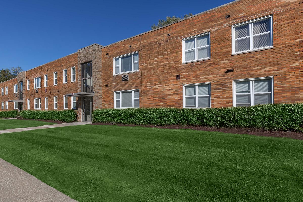 a large brick building with grass in front of a house