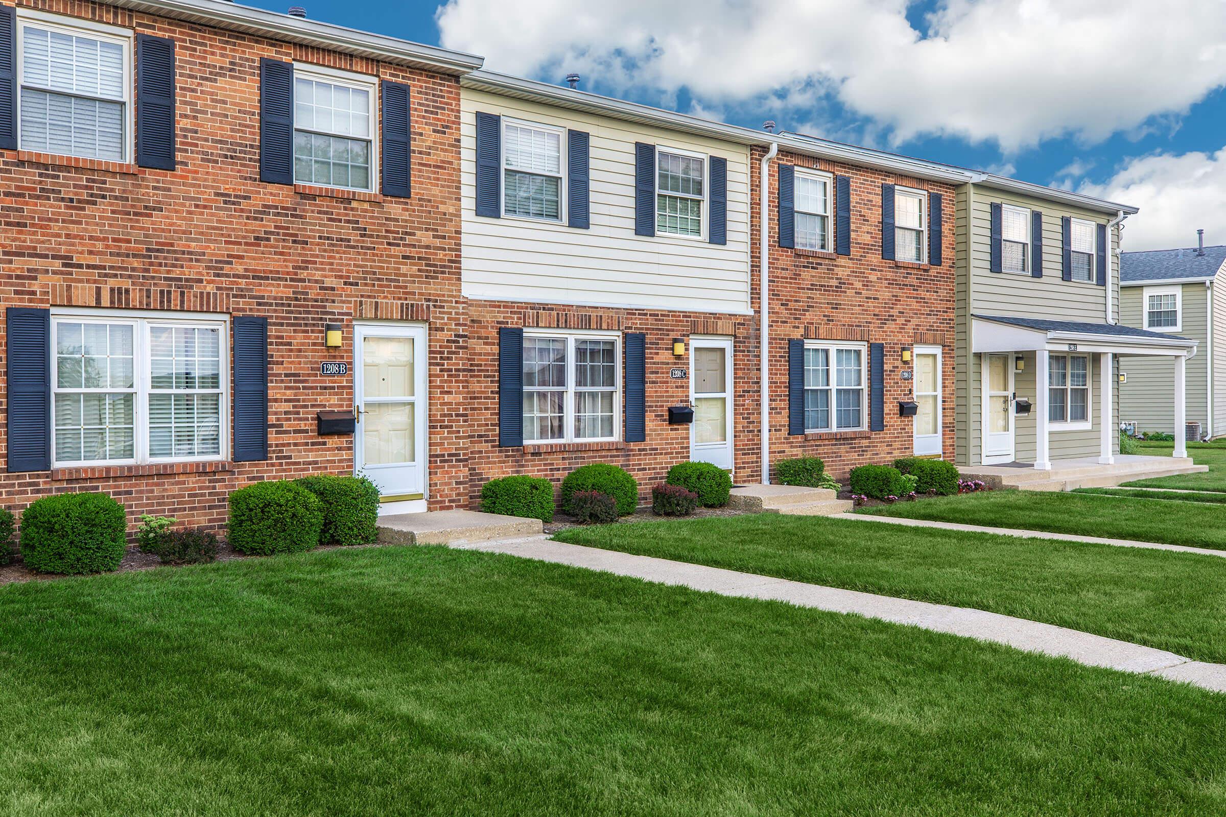 a large brick building with grass in front of a house