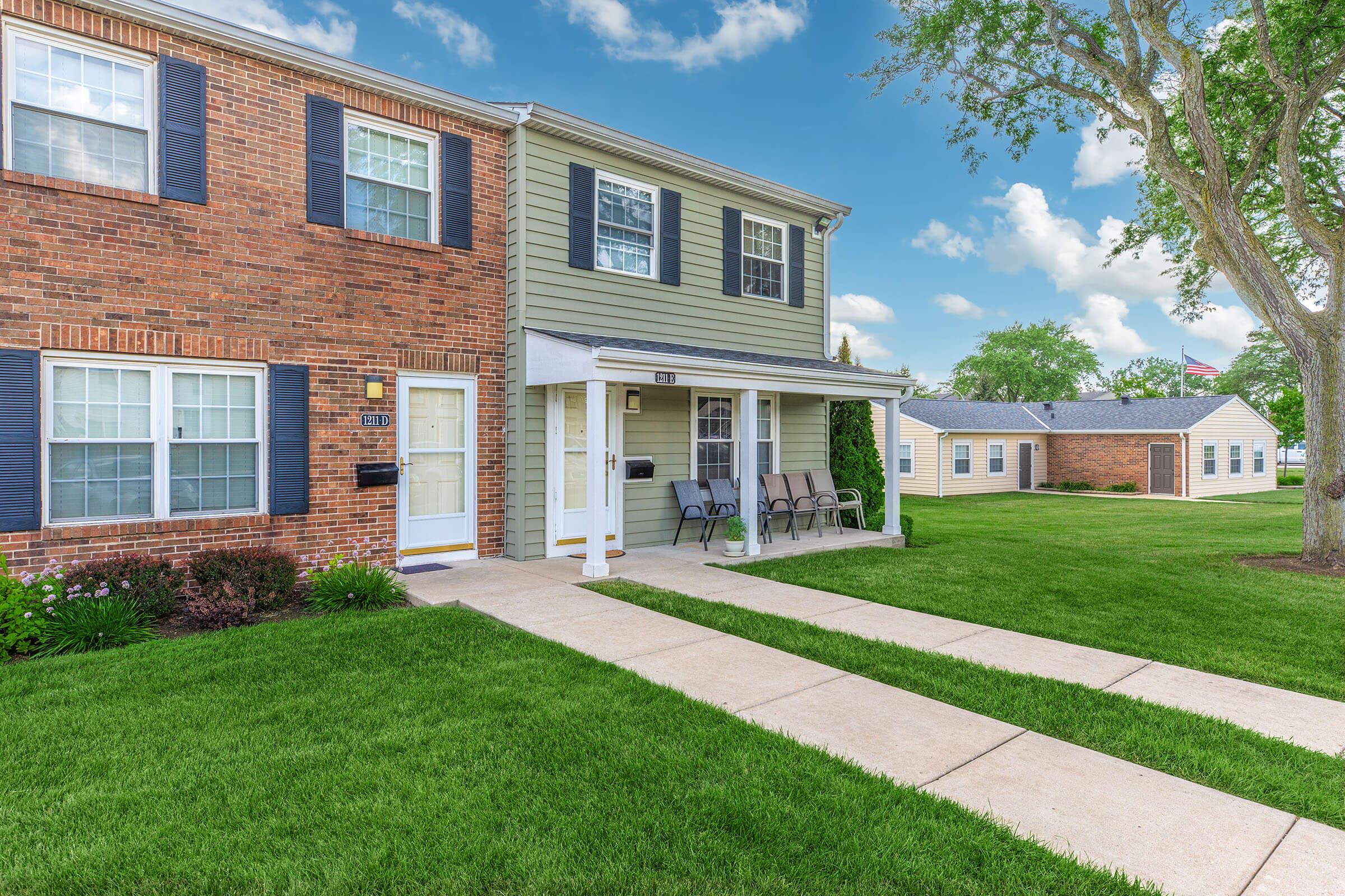 a large brick building with grass in front of a house