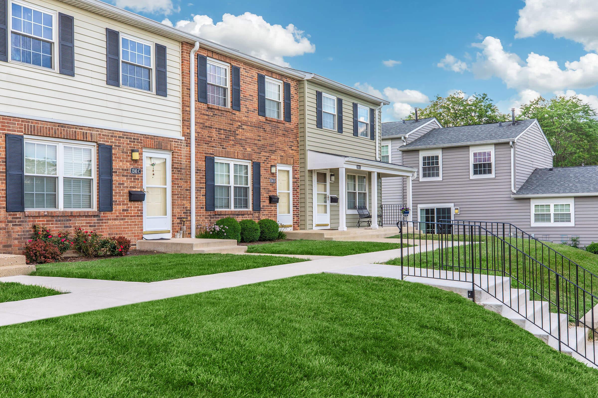 a house with a lawn in front of a brick building