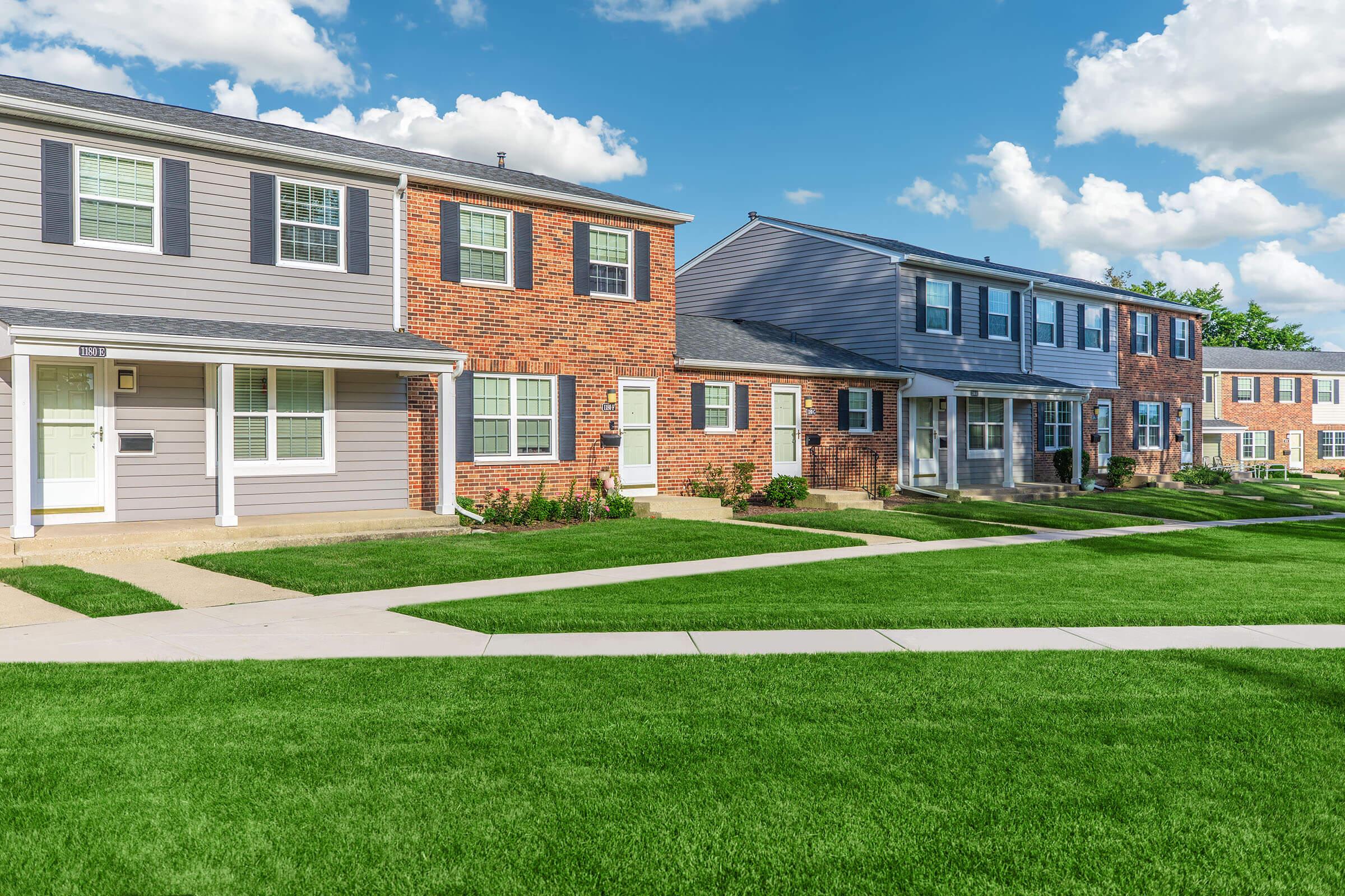 a large brick building with green grass in front of a house