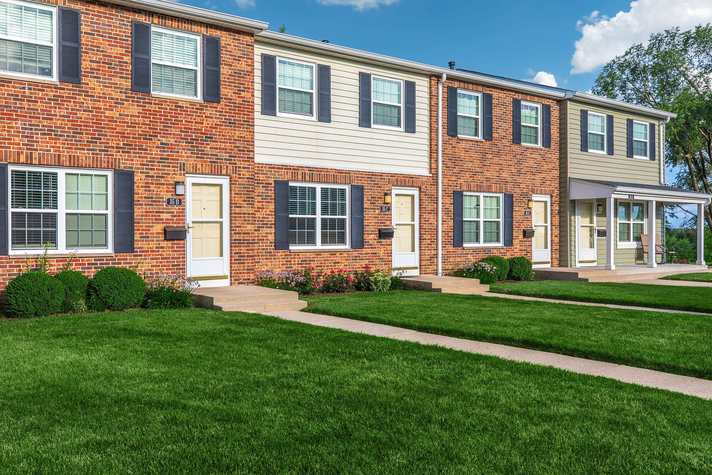 a large brick building with grass in front of a house