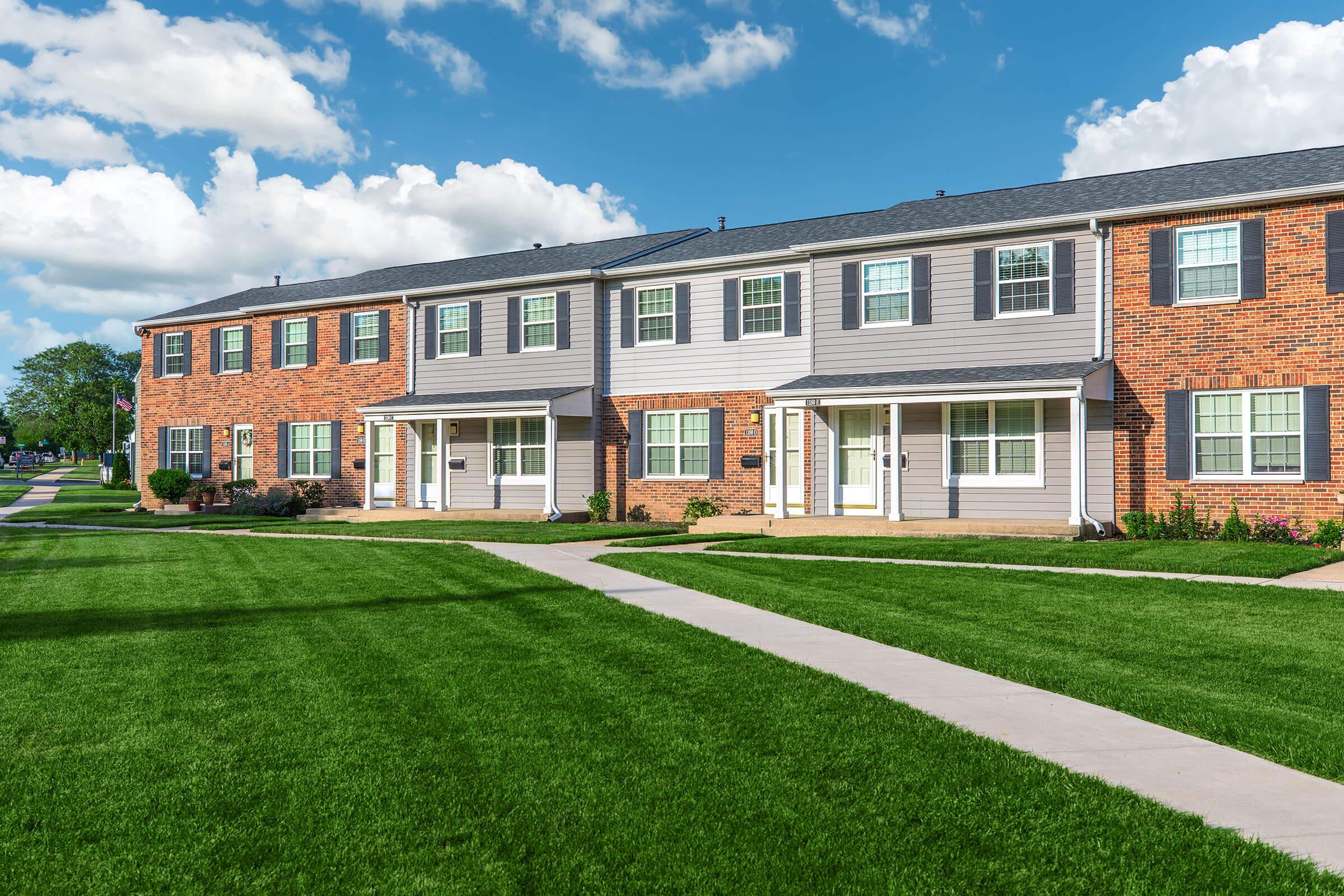 a large brick building with green grass in front of a house