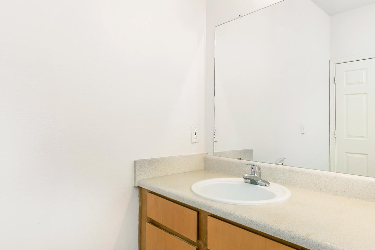 a white sink sitting under a mirror