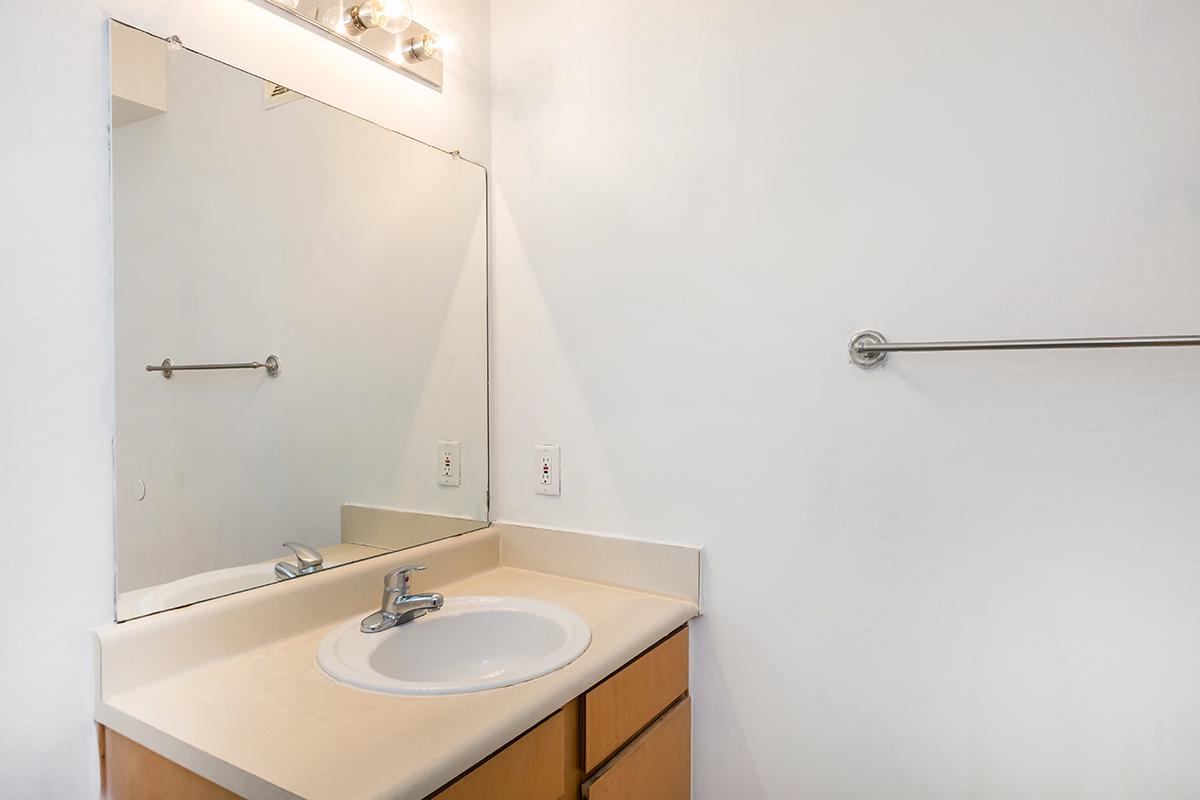 a white sink sitting under a mirror