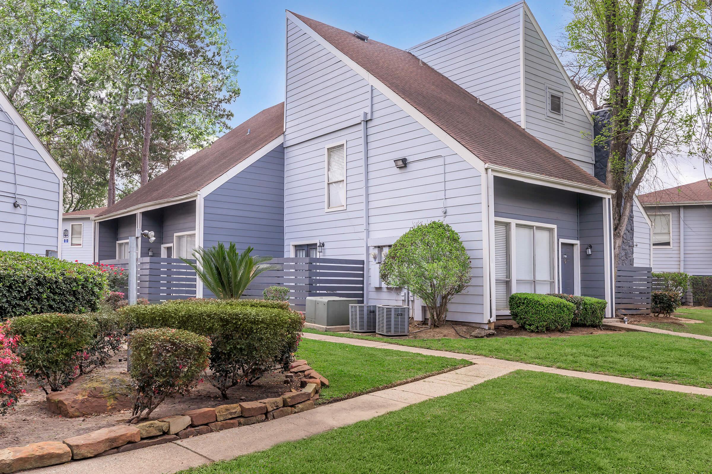 a house with a lawn in front of a brick building