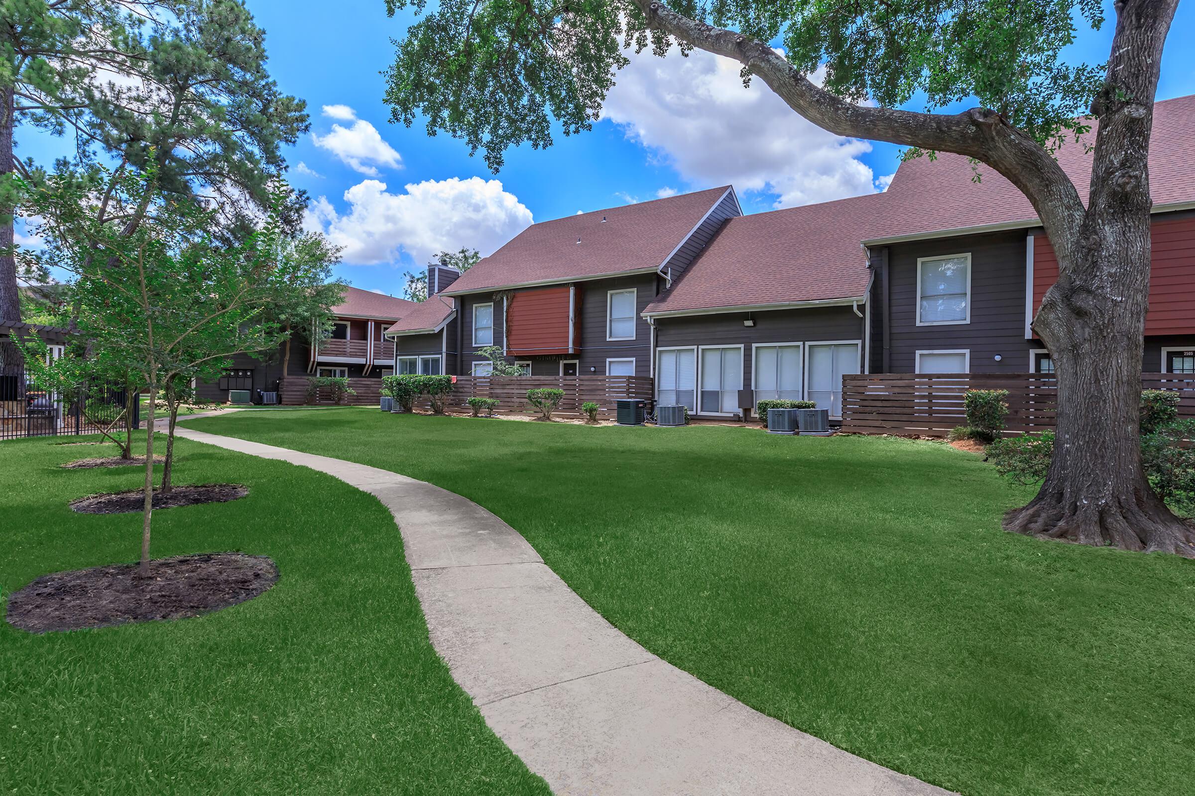 a house with a lawn in front of a brick building