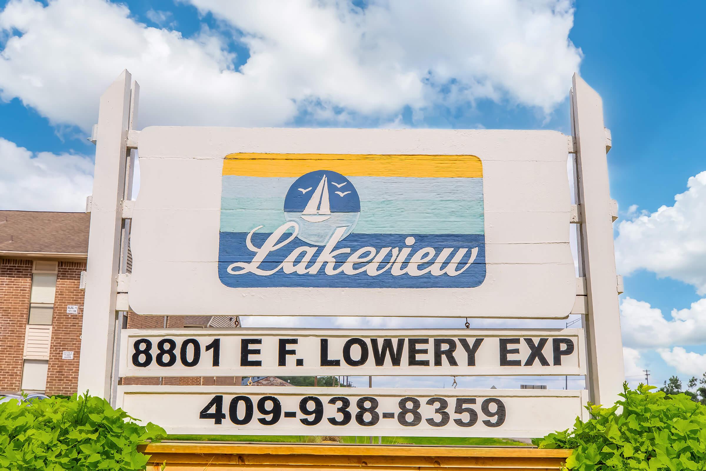 Sign for Lakeview with a sailboat logo and the address "8801 E F. Lowery EXP" along with the phone number "409-938-8359." The background features a bright blue sky with fluffy clouds.
