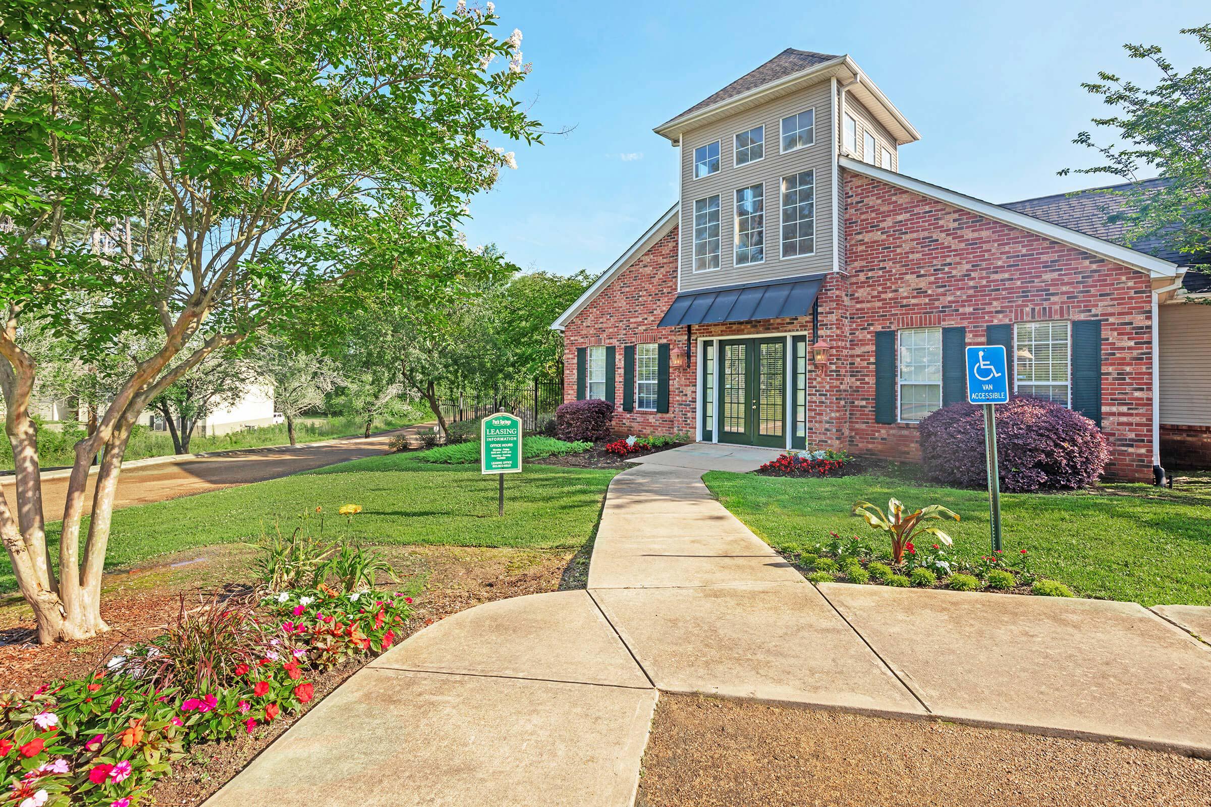 a large brick building with grass in front of a house