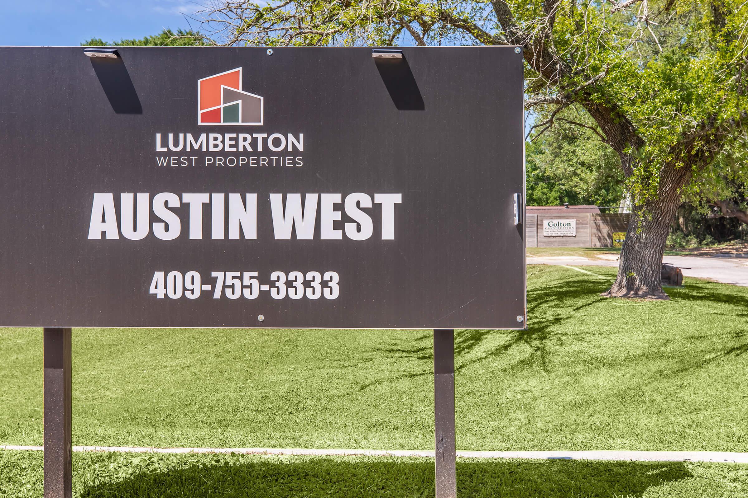 Sign for Austin West Properties by Lumberton West Properties, featuring a modern logo and contact number 409-755-3333. The background includes green grass and trees, with another sign visible in the distance.