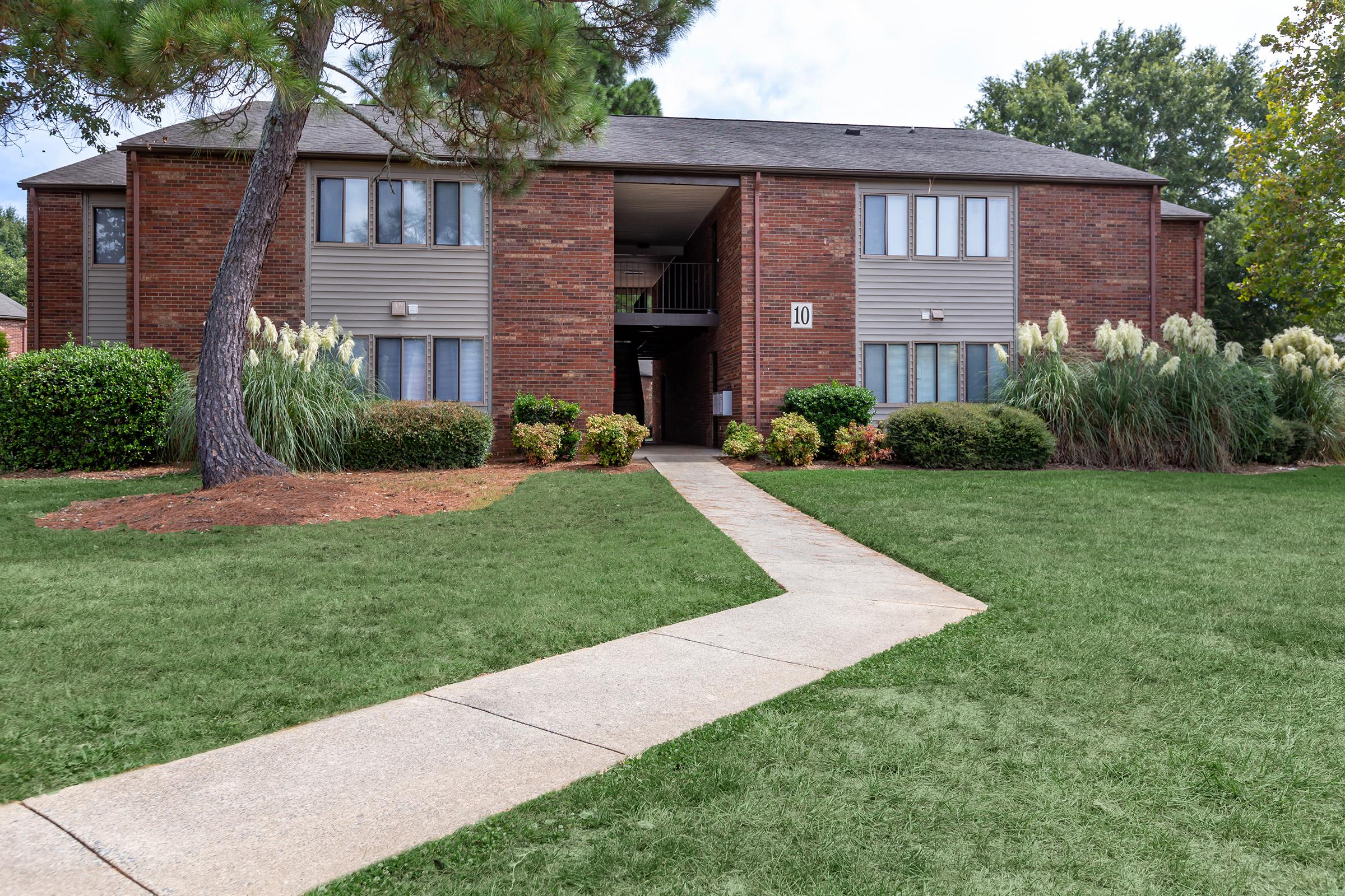 a house with a lawn in front of a brick building