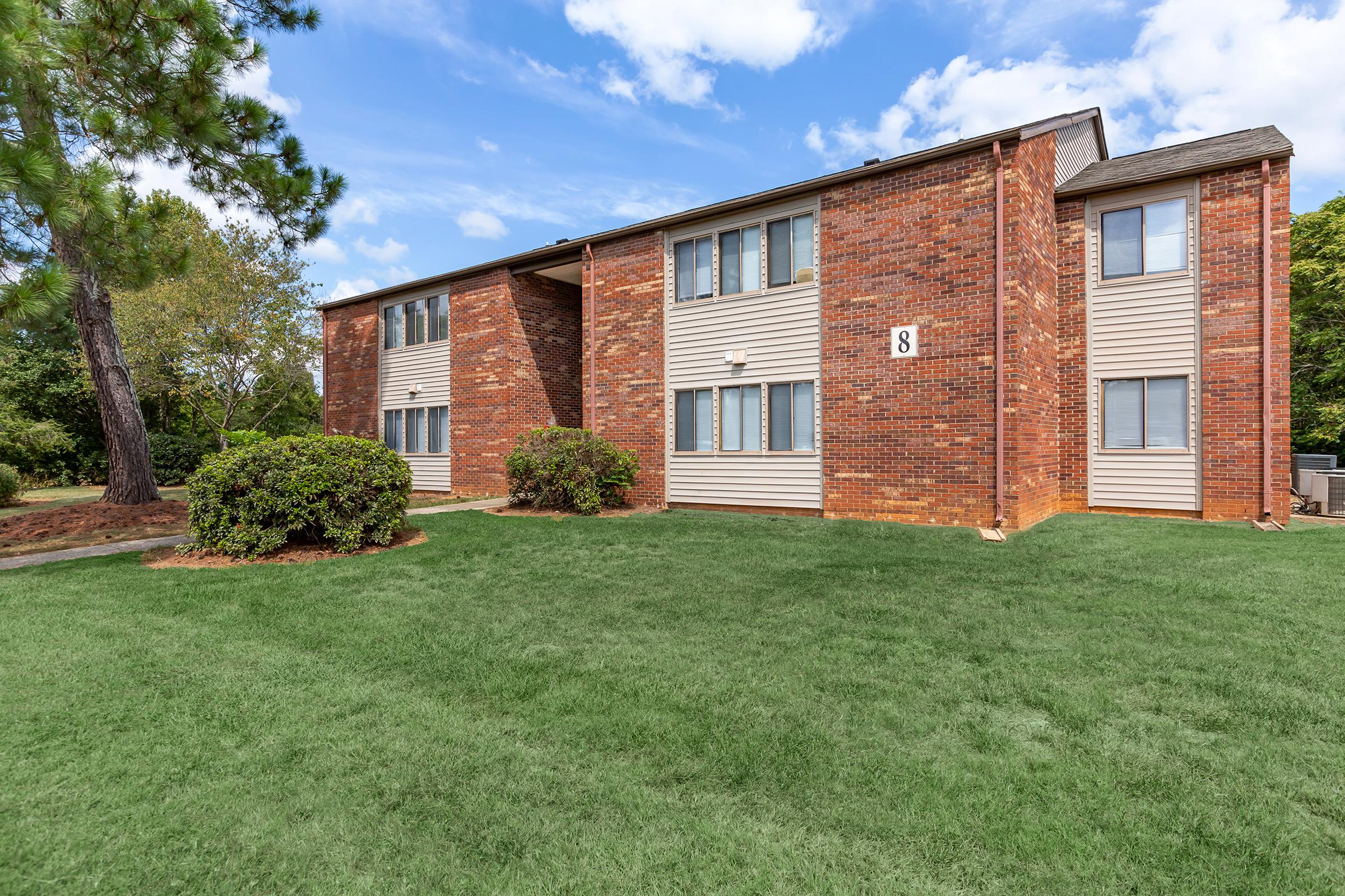 a house with a lawn in front of a brick building