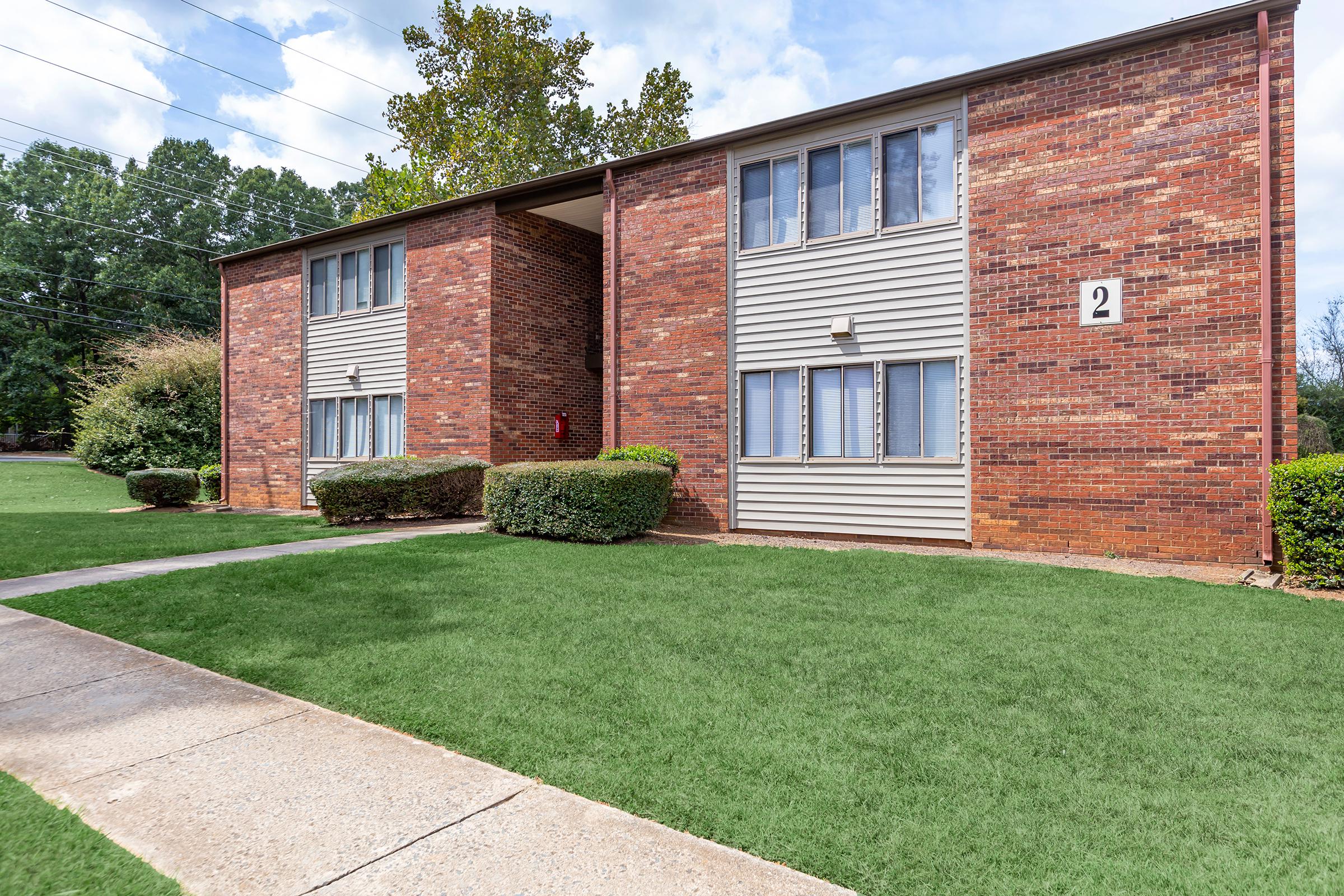 a large brick building with grass in front of a house