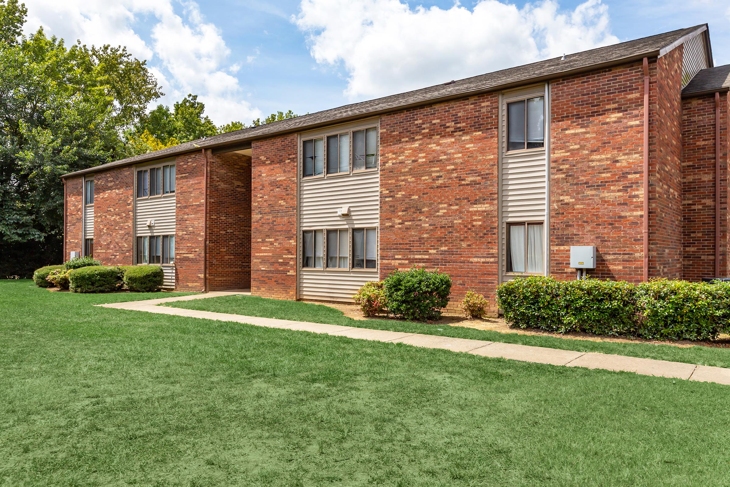 a house with a lawn in front of a brick building