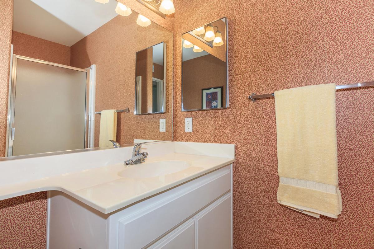 a white sink sitting under a mirror