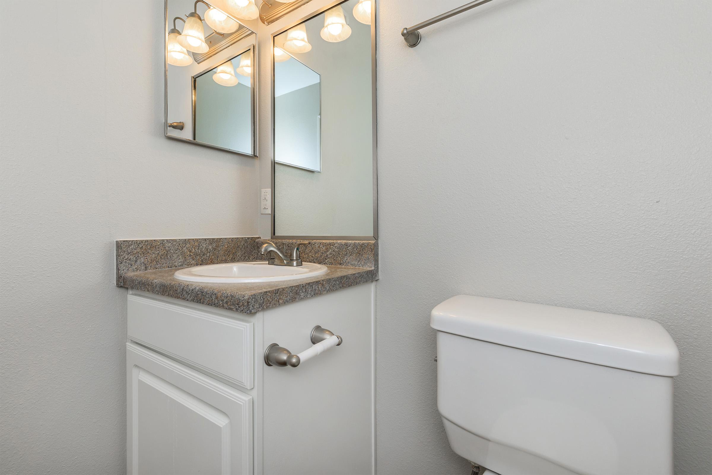 a white sink sitting under a mirror