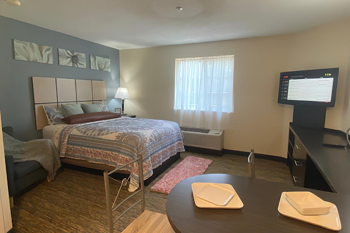 a bedroom with a bed and desk in a hotel room