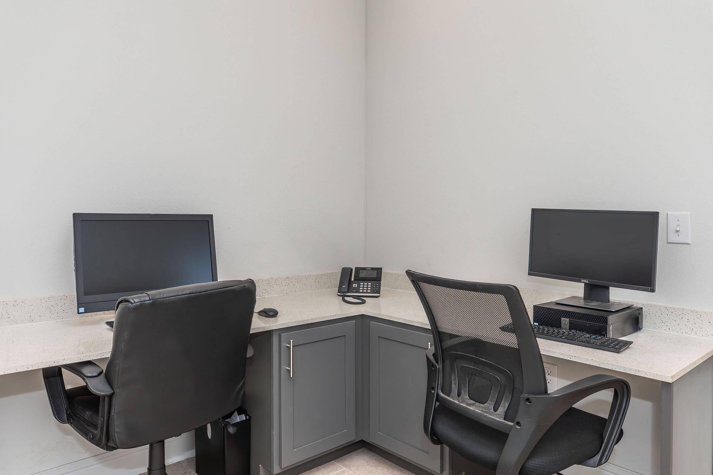 a desk with a computer and a chair in a room