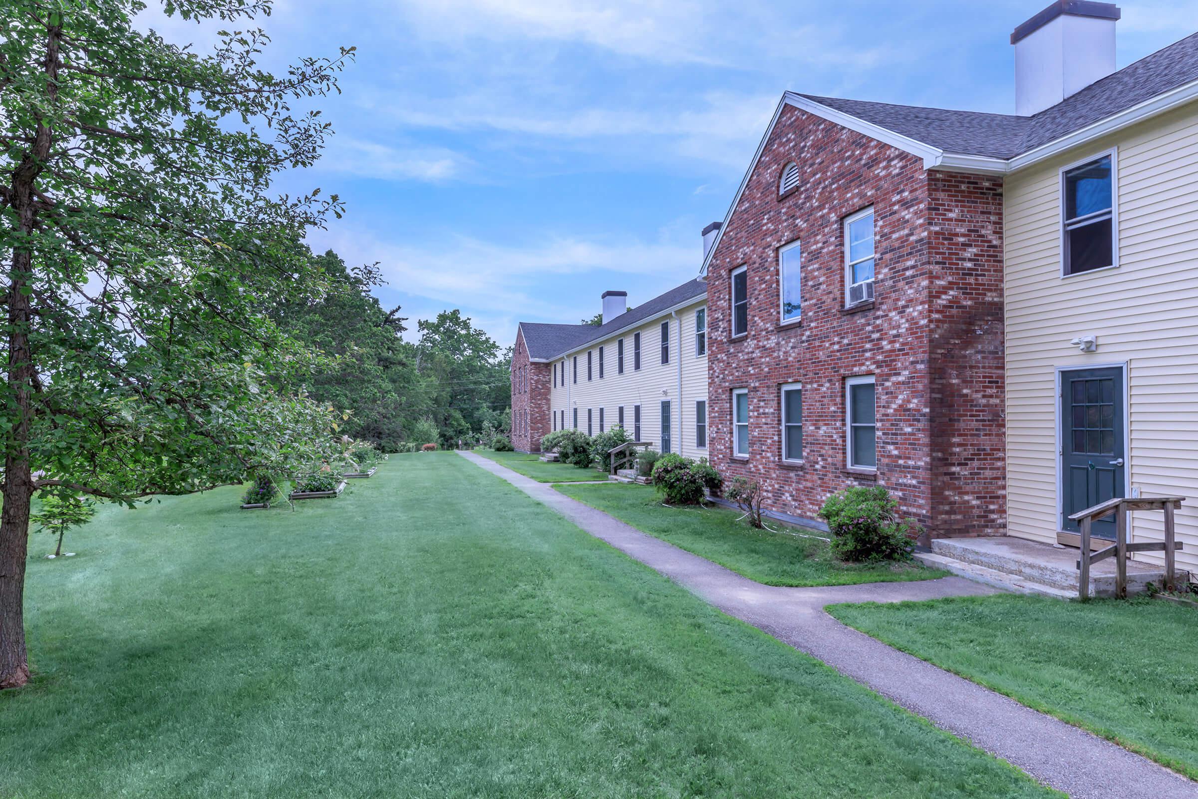 a large brick building with grass in front of a house