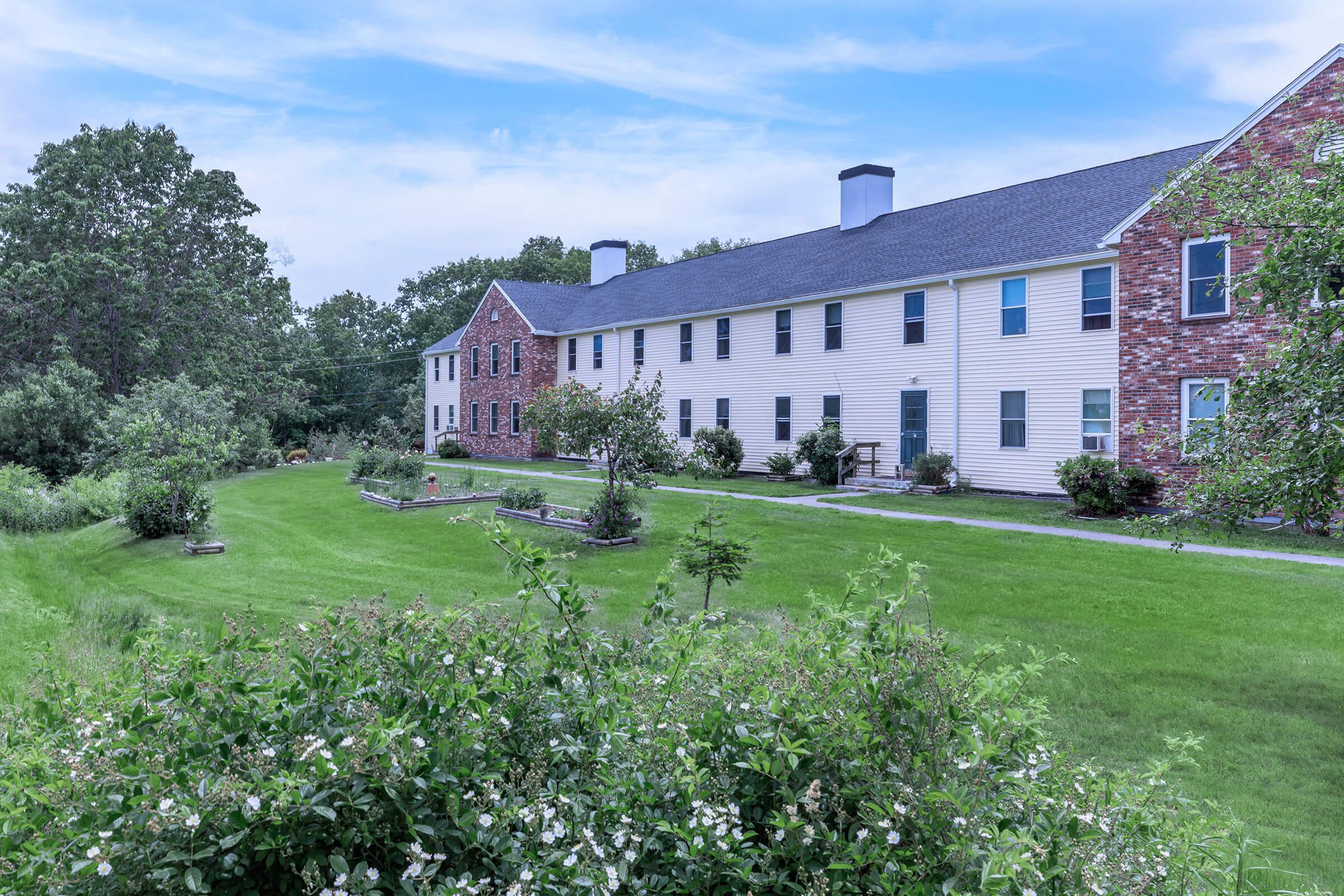 a large brick building with a grassy field