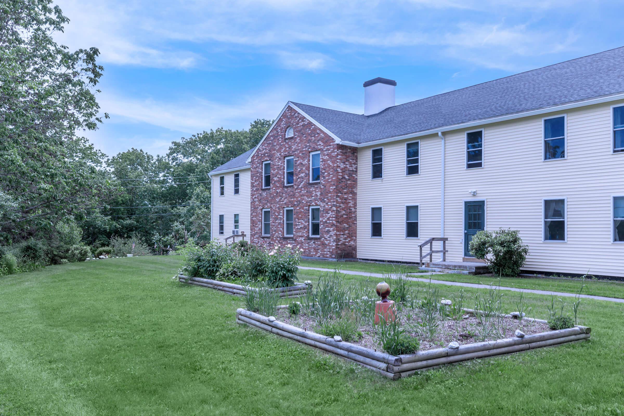 a large brick building with grass in front of a house