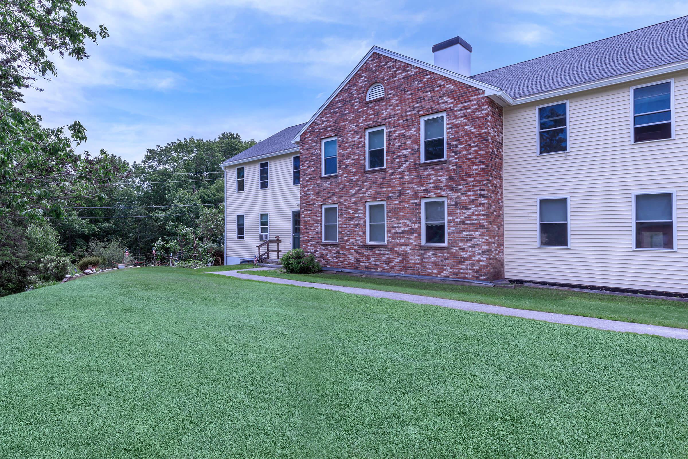 a large brick building with green grass in front of a house