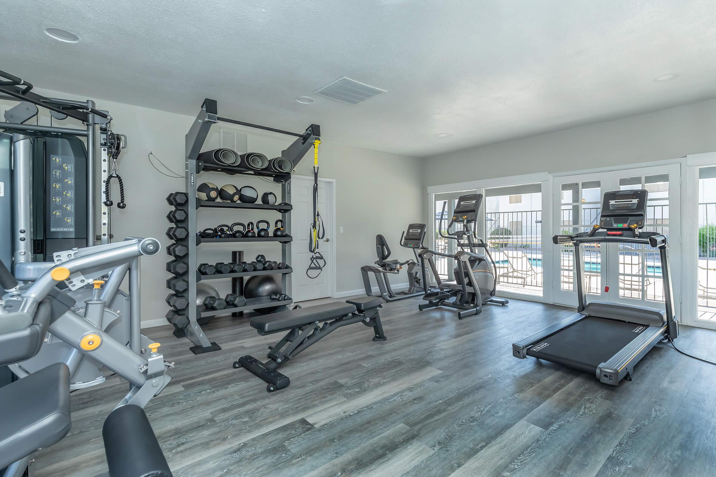 The fitness center with equipment and large windows at Rise at the Preserve.