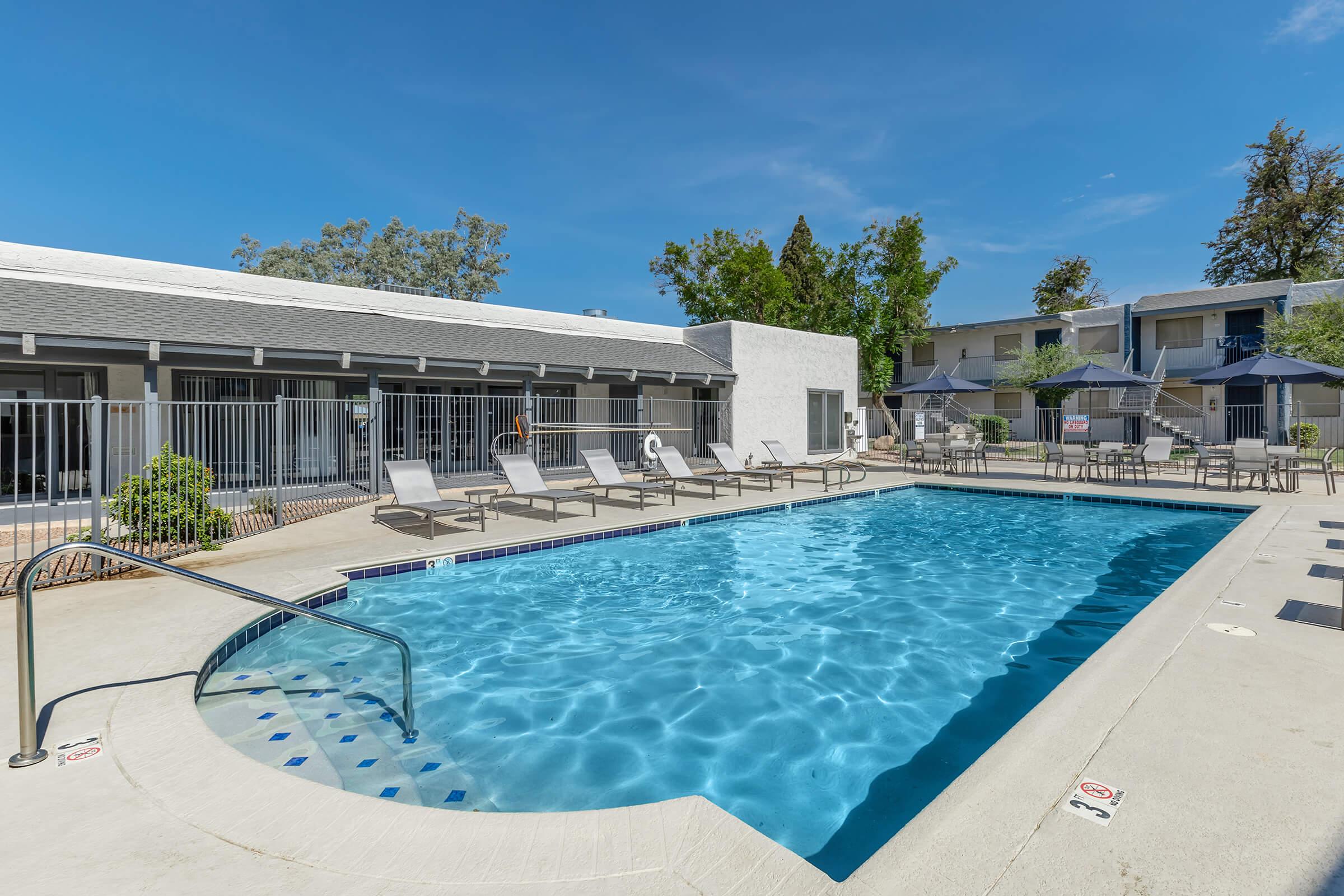 A large pool with loungers surrounded by the apartments at Rise at the Preserve.