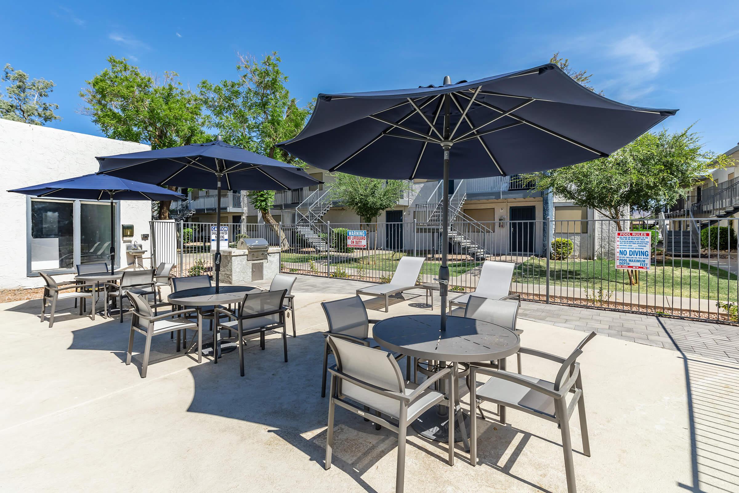 Outdoor dining patio sets with large dark blue umbrellas providing shade