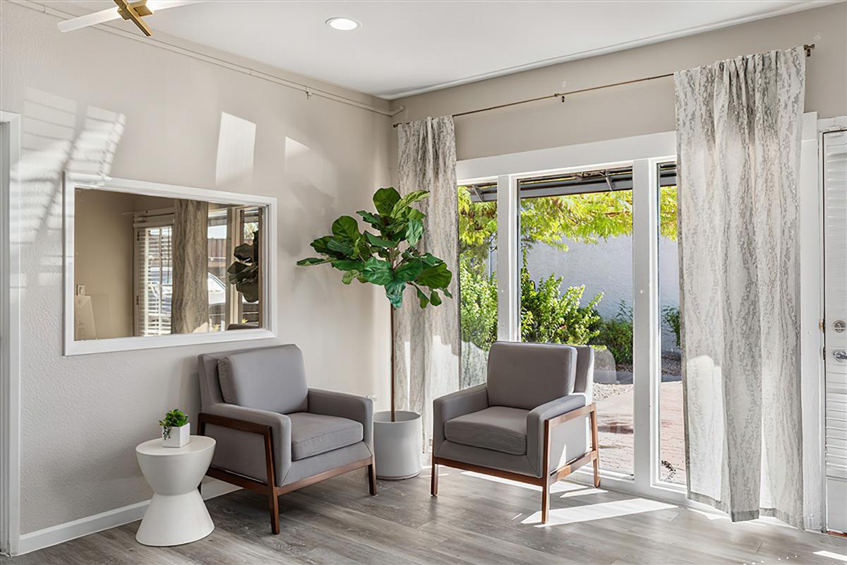 A living room with glass doors and two chairs at Rise at the Preserve. 