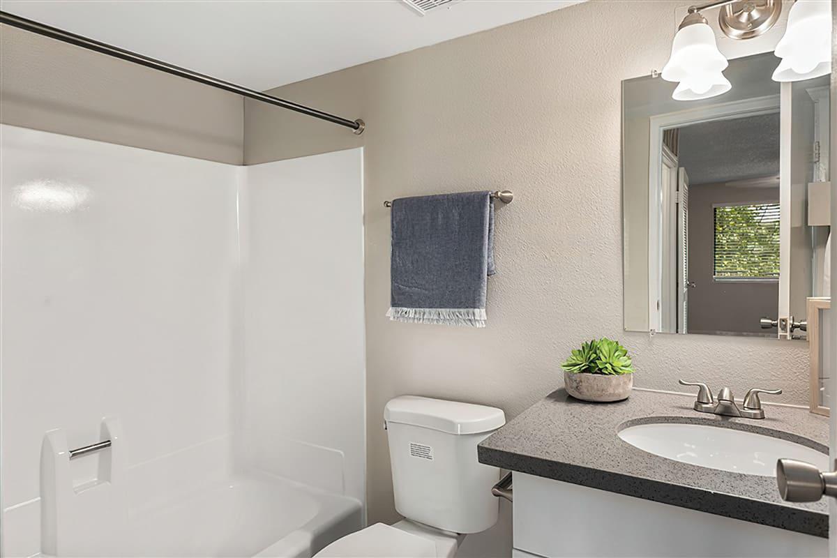 A remodeled bathroom with grey quartz countertops and a tub at Rise at the Preserve.