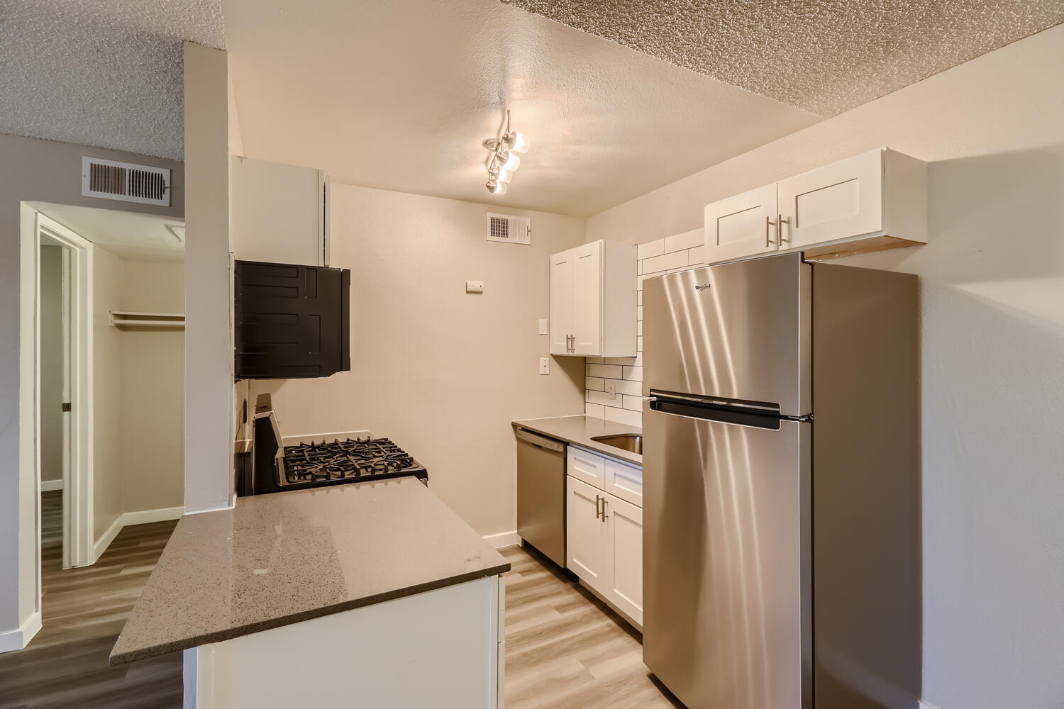 A Rise at the Preserve remodeled kitchen with grey quartz countertops and white shaker cabinets.