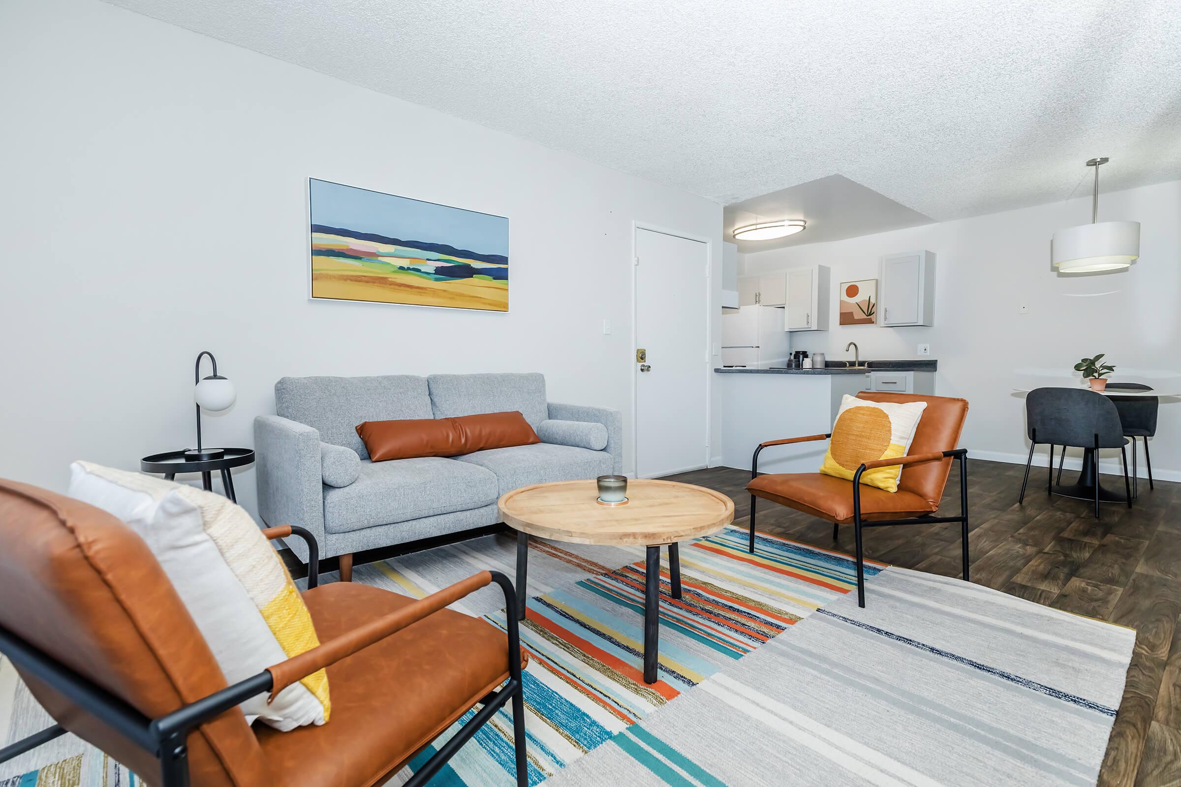 A model apartment living room with a couch and chairs near the kitchen at Rise at the Preserve.