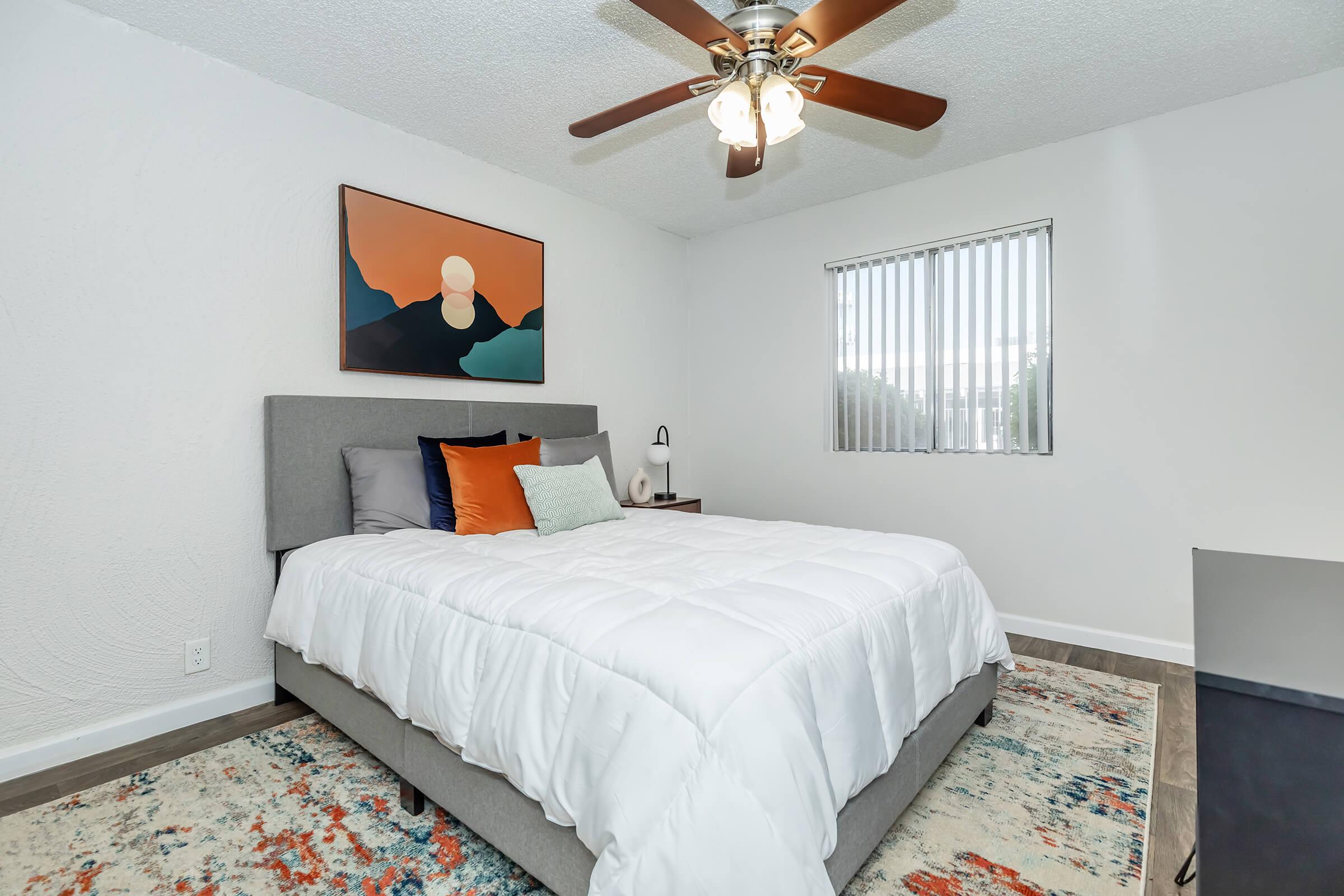 A bedroom at Rise at the Preserve with a window, tile flooring, and a ceiling fan.