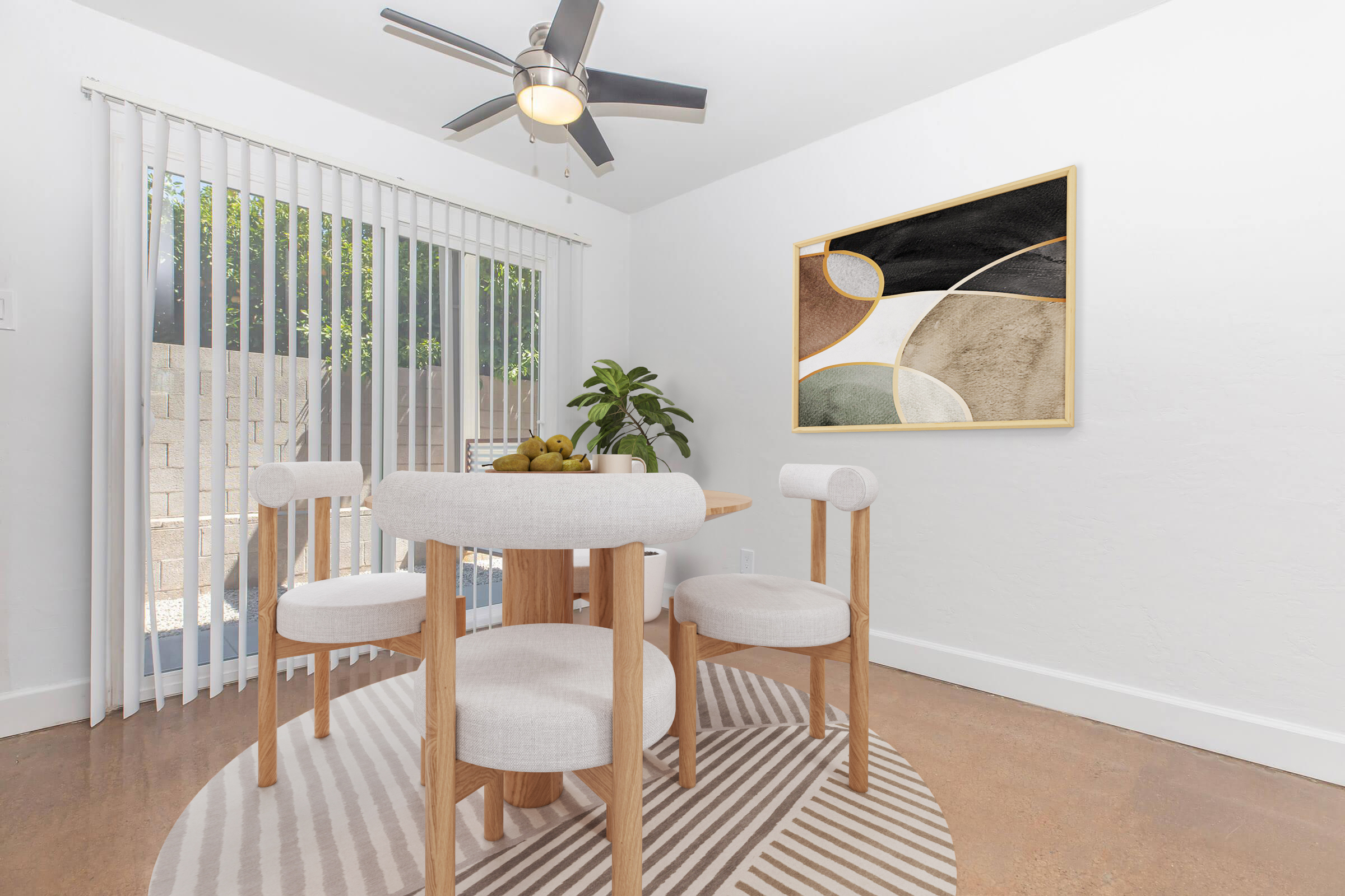 A modern dining area featuring a round wooden table surrounded by upholstered chairs. A stylish area rug is underneath the table, and a large abstract artwork is displayed on the wall. There are indoor plants, and natural light streams through the vertical blinds, enhancing the bright, airy atmosphere.