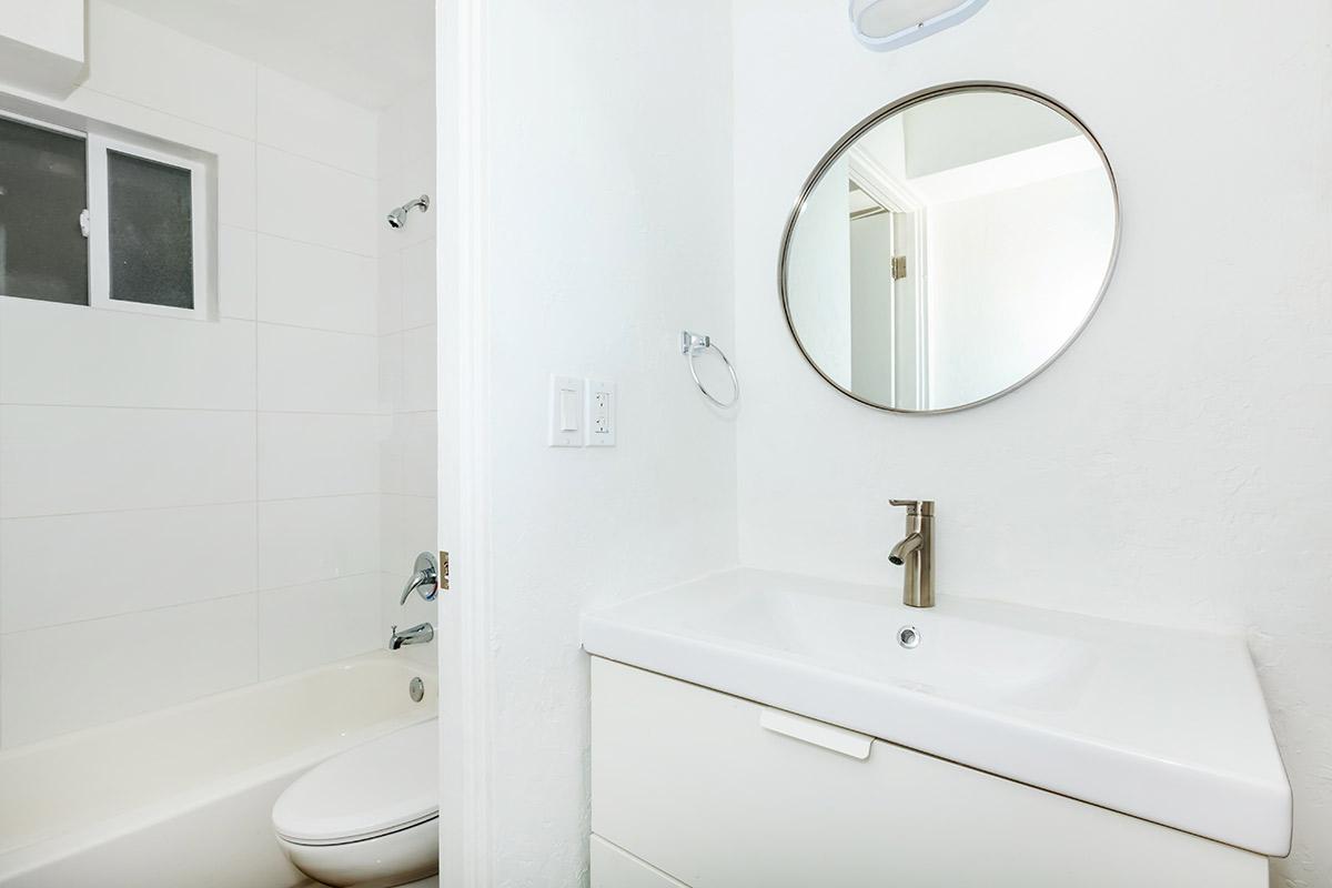 a white sink sitting under a mirror