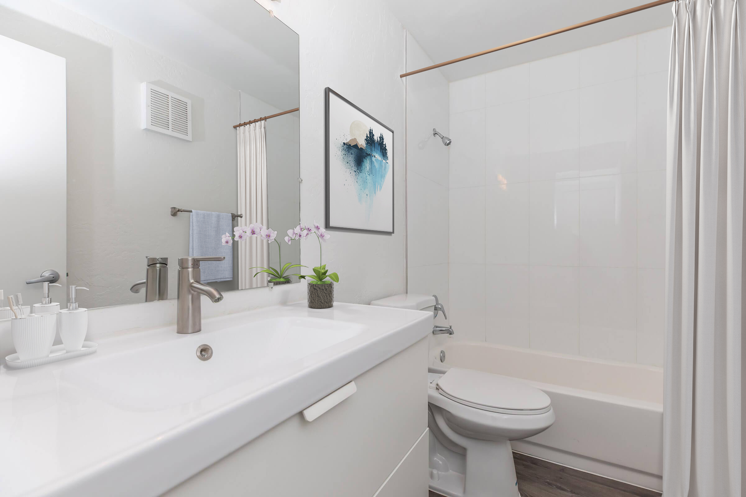 A modern bathroom featuring a white sink with a sleek faucet, a bathtub with a shower curtain, a mirror, and a small potted plant on the counter. A piece of wall art depicting a blue landscape is hung above the sink, adding a touch of decor to the clean and minimalistic space.
