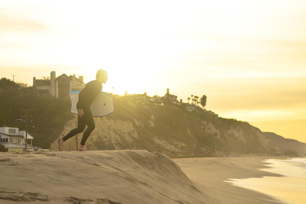 a male surfer running to the ocean