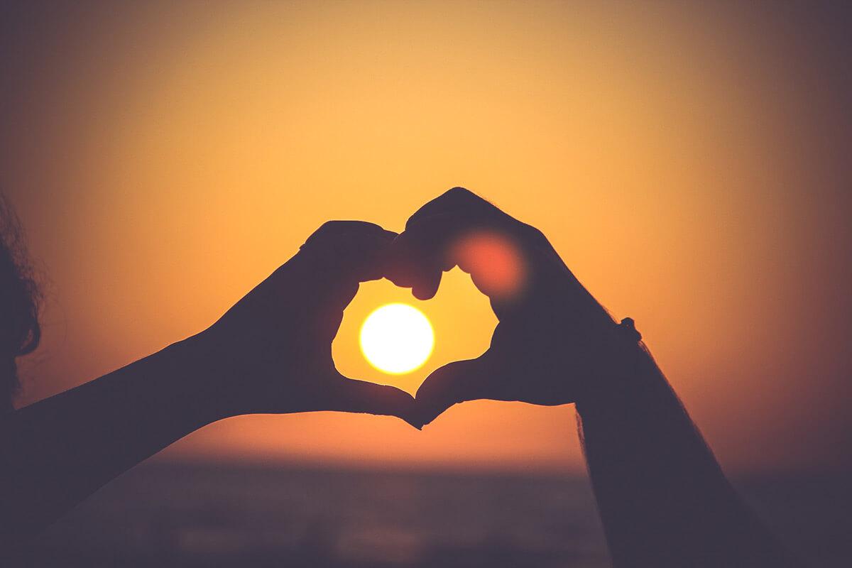 a close up of a sunset with hands in the shape of a heart