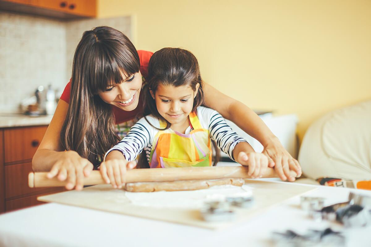 a woman and child using a rolling pin