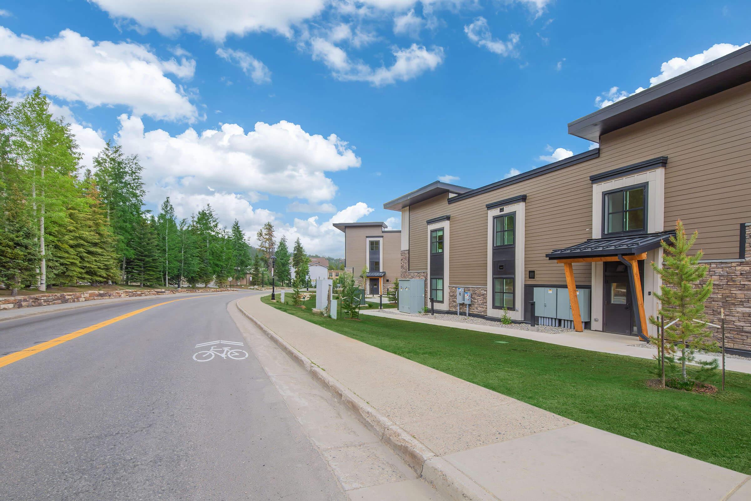 an empty road with grass on the side of a building