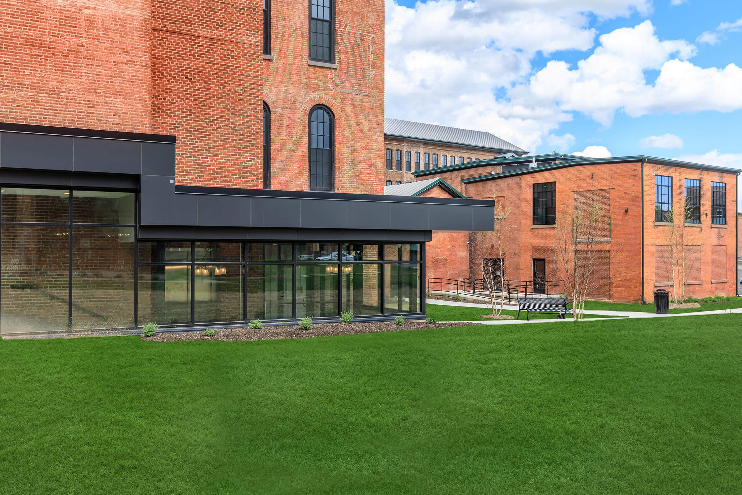 a large brick building with green grass